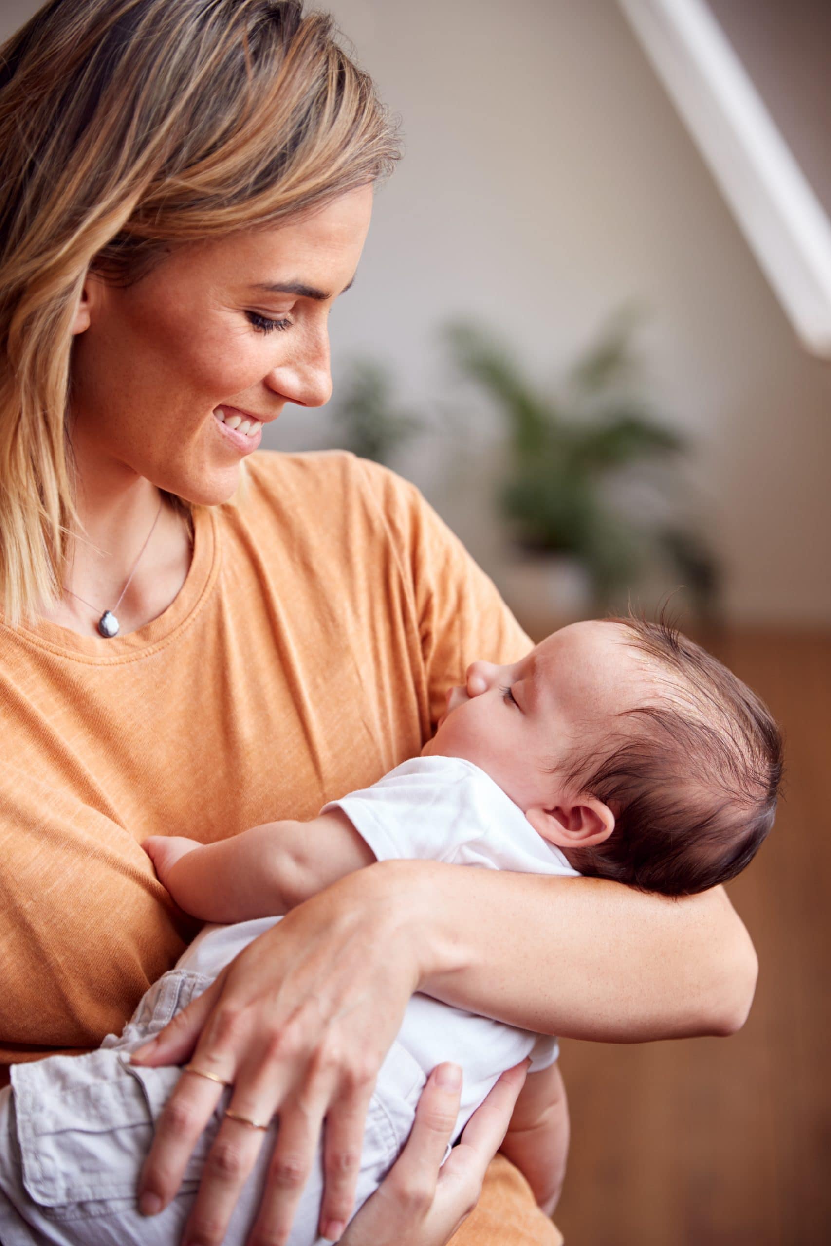 Loving Mother Holding Newborn Baby At Home In Loft Apartment