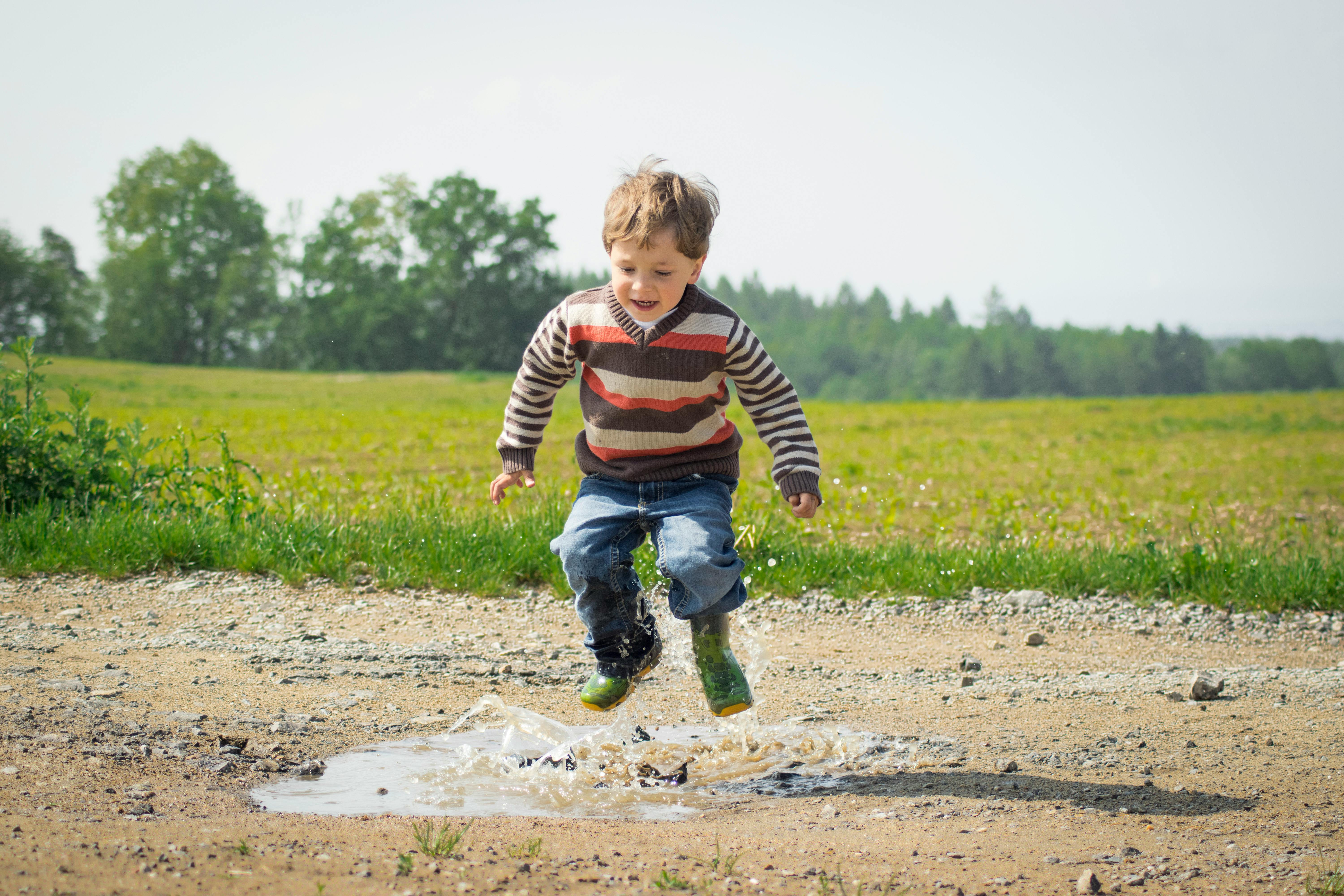 child jumping in puddle