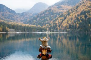 baby on parents shoulders in front of lake and mountains