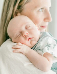 Mother holding sleeping baby on her shoulder