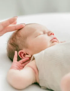 Hand touching head of sleeping baby