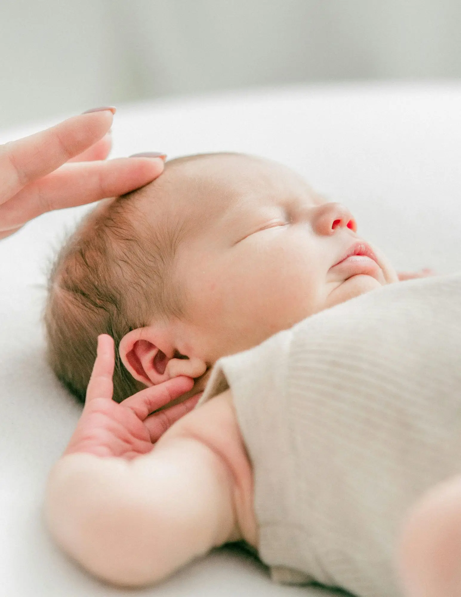 Hand touching head of sleeping baby