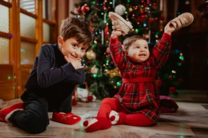 Two children sitting in front of a Christmas tree