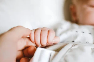 Baby holding parent's finger